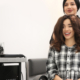 A woman smiles as her hairdresser does a professional wig install.